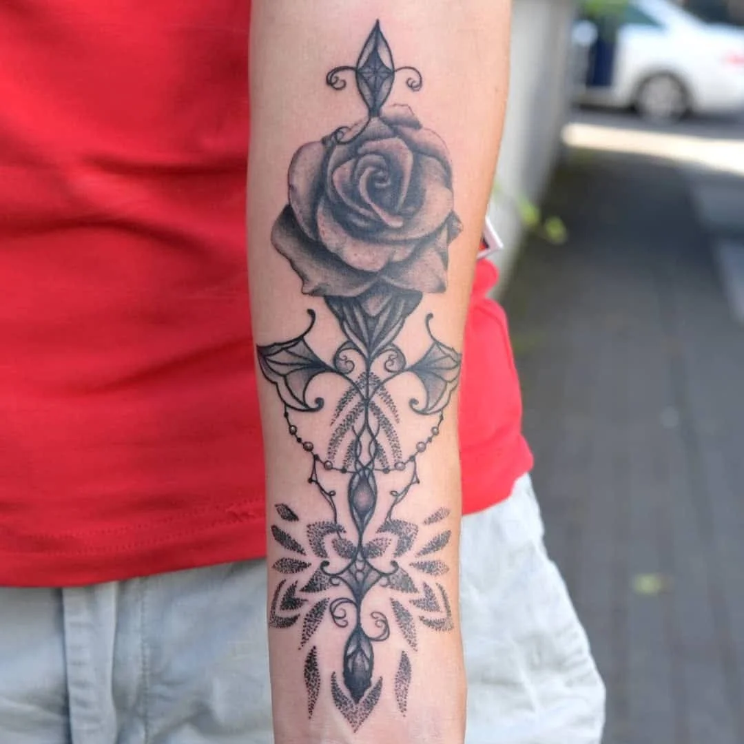 Realistisches Rosen-Tattoo kombiniert mit feinen Mandala-Elementen am Arm, gestochen von Artist Kim bei Living Pictures.